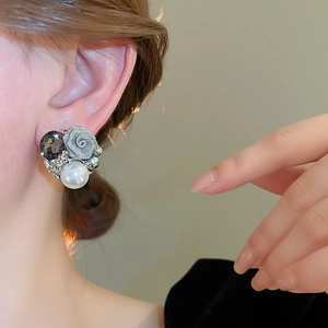 Détail de boucles d'oreilles rose vintage avec perle et cristal gris sur un mannequin