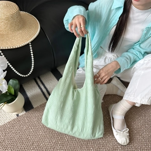 Detail of mint green seersucker tote bag texture held by model in a casual setting