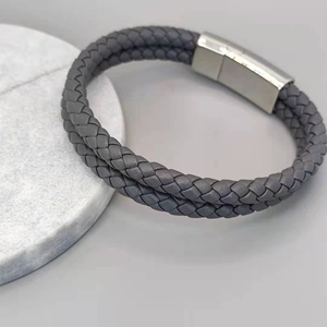 Close-up of double-layer gray braided leather bracelet with polished magnetic steel clasp