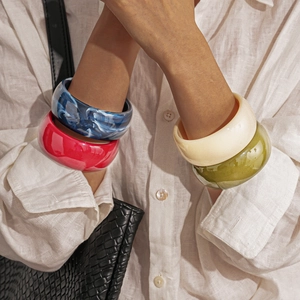 Fashionable colorful acrylic marble texture bangles on model wrists with bag