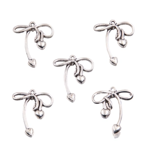 Detailed view of silver cherry bow pendants for DIY jewelry crafting on white background