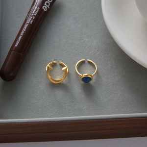 Detail of minimalist gold-plated adjustable rings with inlaid blue gemstone on display
