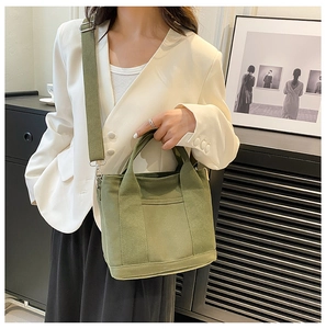 Detail of army green canvas tote bag featuring a front pocket and adjustable strap