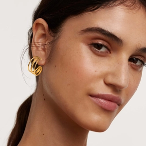 Detailed view of model wearing three-layer golden C-shaped hoop earrings in stainless steel
