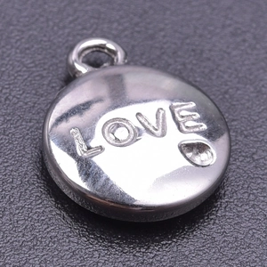Macro detail of silver round stainless steel LOVE pendant with small heart for DIY jewelry
