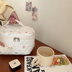Détail d'une trousse à maquillage matelassée fleurie avec fermetures en métal