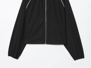 Detail of black nylon jacket showing silver zipper, side pockets, and white piping on sleeves