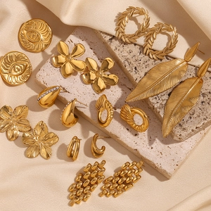 Collection of 18K gold plated stainless steel stud earrings on stone and silk background