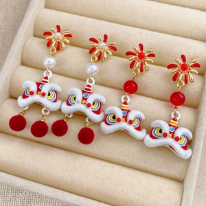 Close-up of Chinese lion dance earrings with red pom-poms and white pearls on velvet