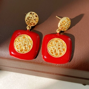 Dettaglio di eleganti orecchini vintage a goccia in smalto rosso con motivi in filigrana