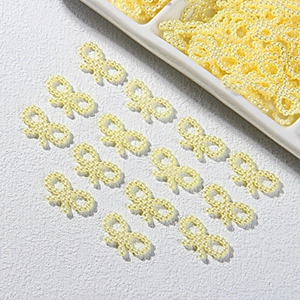 Close-up of pale yellow pearl bow tie beads for DIY crafts and phone case decoration