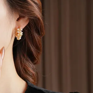 French vintage gold U-shaped earrings with pearls and zircon on model in warm lighting