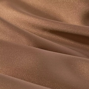 Detailed macro view of the smooth brown satin fabric texture with elegant drapes