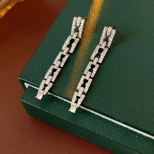 Détail de boucles d'oreilles chaînes argentées serties de zircons sur un coffret vert
