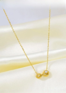 Close-up of a gold titanium steel infinity necklace with a sparkling round zircon