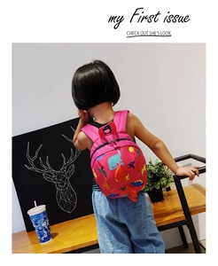 Detail of red dinosaur backpack showing side spikes and colorful cartoon patterns