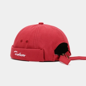 Detail view of red canvas docker cap featuring white Forever embroidery and metal buckle