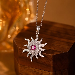 Macro view of sun pendant with red center stone and pavé zircons on silver chain