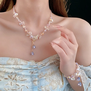 Close-up of pink and purple crystal tassel necklace and matching bracelet on model