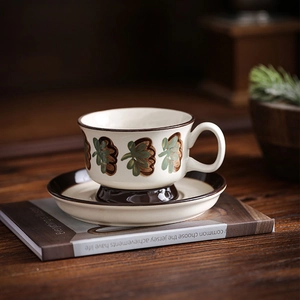 Detailed close-up of ceramic coffee cup with hand-painted retro leaf pattern and brown trim