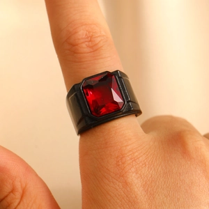 Nahaufnahme eines Herrenrings aus mattschwarzem Metall mit einem großen roten Zirkoniastein