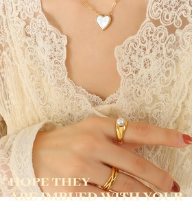 Detail of a gold heart necklace with white mother-of-pearl shell inlay and pearl ring