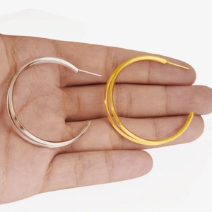 Detailed comparison of gold and silver hollow hoop earrings on hand showing size