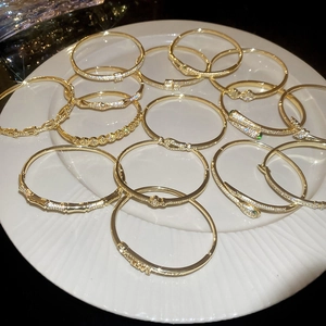 Detail of 18k gold plated snake head bracelet and stone-set jewelry on white plate