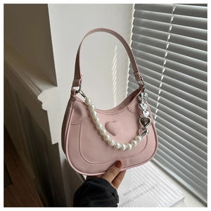 Pink saddle bag featuring white pearl handle and silver heart chain detail