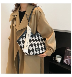 Detail of a chic black and white checkered canvas bucket bag on a model's shoulder