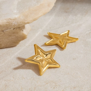 Detailed view of 18K gold plated star stud earrings on a natural stone surface