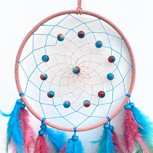 Handmade pink and blue dream catcher with feathers and beads on white background