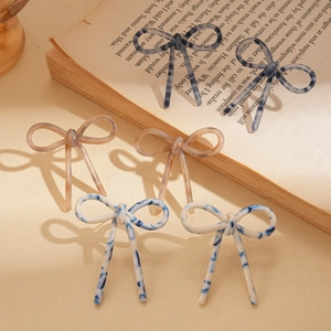 Elegant acetate bow earrings in blue marble and beige tortoise shell on vintage book