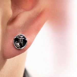 Detailed macro view of vintage embossed silver stud earring with punk relief patterns
