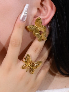 Close-up of a model wearing a gold butterfly earring and matching镂空 hollow-out ring