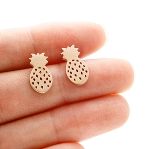 Minimalist gold pineapple stud earrings made of stainless steel shown on a fingertip