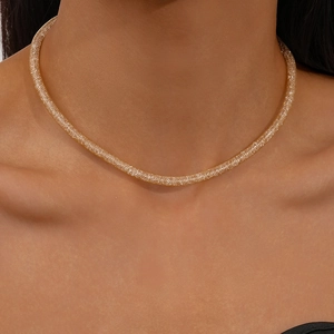 Close-up of a woven gold mesh tube necklace with shimmering zircon accents on model