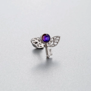 Silver titanium steel ear stud featuring winged key design with purple zircon gemstone
