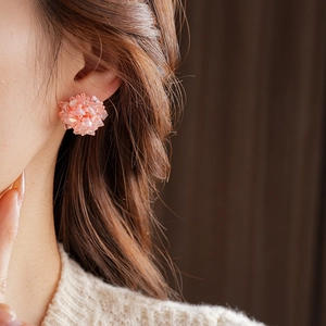 Close-up of pink beaded flower cluster earrings worn by a model in soft lighting