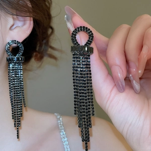 Close-up of elegant black rhinestone tassel earrings worn by a model in soft lighting