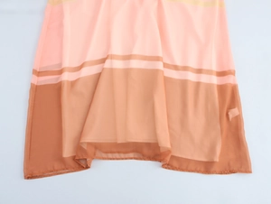 Detail view of pink and brown chiffon dress hem with soft draped fabric and sheer texture