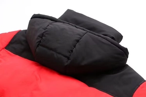 Détail de la capuche et du col d'une doudoune matelassée bicolore rouge et noire