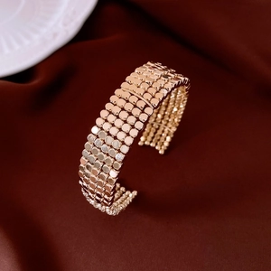 Macro detail of gold multi-layered circular beaded open cuff bracelet on silk