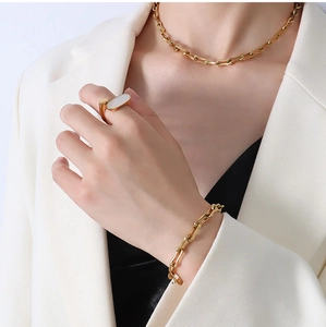 Close-up of 18k gold plated U-link chain jewelry set worn on a model with white suit