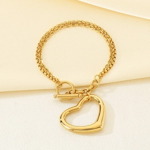 Détail d'un collier chaîne doré avec pendentif cœur ajouré et fermoir à bascule