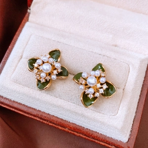 Gros plan sur des boucles d'oreilles fleurs vintage en émail vert, perle et plaqué or 18k
