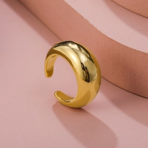 Close-up of a minimalist gold open ring with a polished curved surface on pink stairs