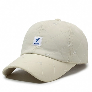 Beige quilted padded baseball cap with bird embroidery logo and minimalist warm design