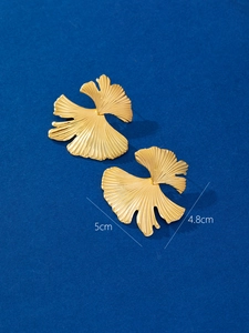 Macro detail of large 18K gold plated stainless steel ginkgo leaf earrings with brushed texture