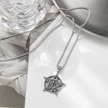Close-up of a silver titanium steel necklace with a hexagram star pendant on white surface